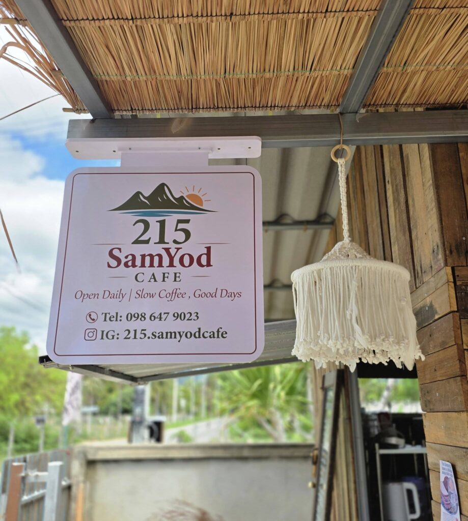 ที่นั่งเก้าอี้ผ้าใบชายหาดและชิงช้าไม้ใต้ร่มเงาต้นไม้ใหญ่ริมทะเลที่ร้าน บ้านปาล กาแฟสด