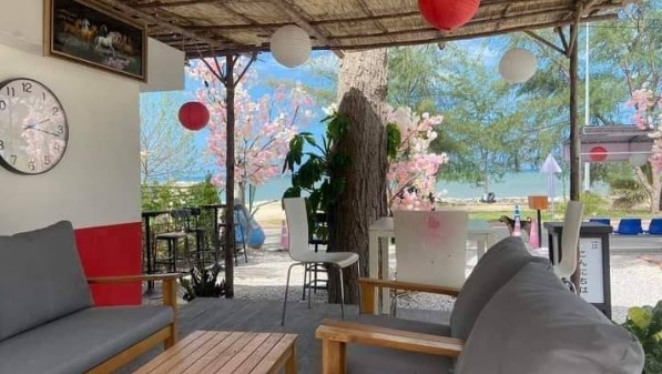 โซนที่นั่งโซฟาผ้าสีเทารับลมทะเลที่ร้าน Cha Chi Lay ชา ชาย เล คาเฟ่ริมหาดตกแต่งสไตล์ญี่ปุ่นด้วยต้นซากุระและโคมไฟ