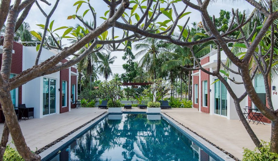 บ้านพักวิลล่าสีขาวมีดาดฟ้าและสระว่ายน้ำยาวส่วนกลางที่ The Beach Village Resort สามร้อยยอด