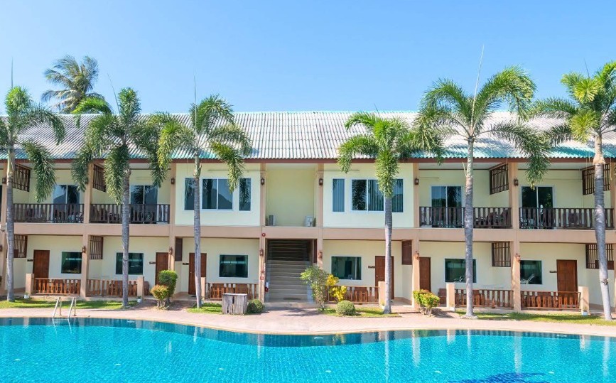 อาคารห้องพักและสระว่ายน้ำกลางแจ้งล้อมรอบด้วยทิวต้นปาล์มที่ The Green Beach Resort สามร้อยยอด