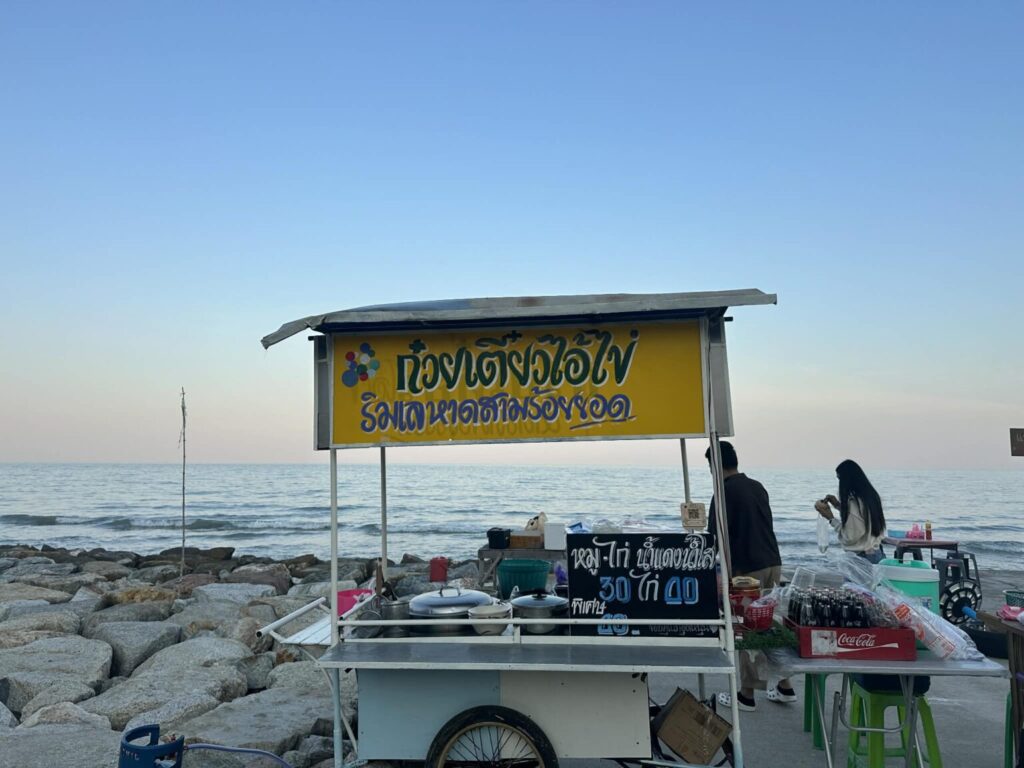 รถเข็นร้านก๋วยเตี๋ยวไอ้ไข่ป้ายสีเหลือง ตั้งอยู่ริมชายหาดสามร้อยยอดพร้อมวิวทะเลกว้างยามเย็น